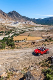Tourists explore Nysiros with a red car on a gravel road