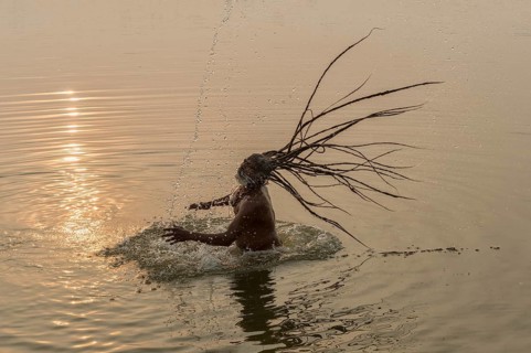 Rom Baba with water spraying from his flying dreadlocks in the river Ganges