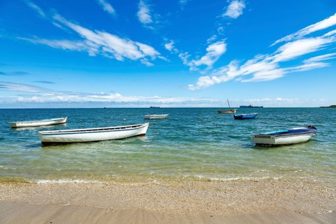Fishing boats in turquoise green water on the beach at Bain des Dames