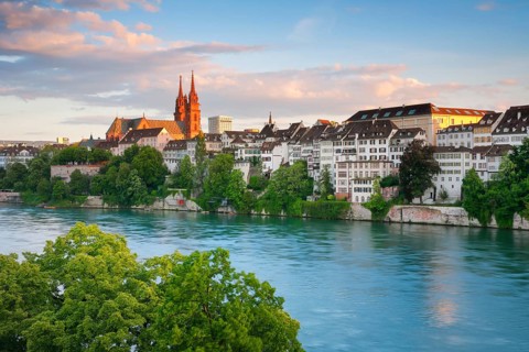 View of the Basel Cathedral in the middle of the old town of Basel with the turquoise Rhine River in the foreground