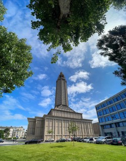 Wide-angle shot of St Joseph's Church with blue sky and framed by trees in Le Havre