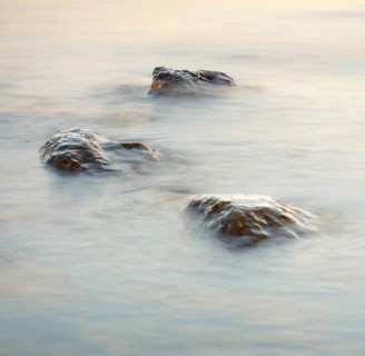 Light play and stones in the water at sunrise photographed with slow shutter speed