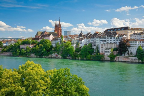 View of the Basel Cathedral in the middle of the old town of Basel with the turquoise Rhine River in the foreground