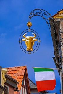 Guild sign of the Gasthof Zum Ochsen above an Italian national flag in Ladenburg