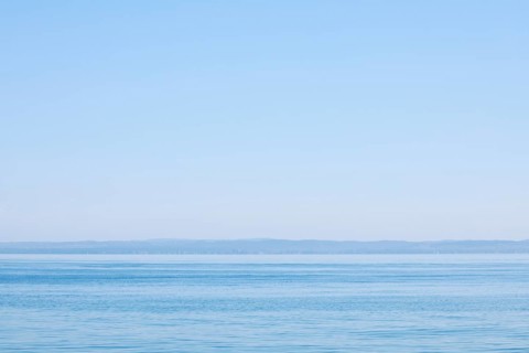 View from Arbon over blue shimmering Lake Constance in sunny weather and blue sky in summer