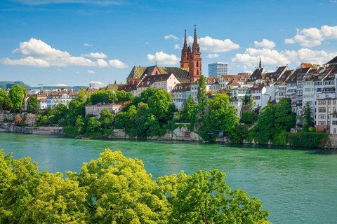 View of the Basel Cathedral in the middle of the old town of Basel with the turquoise Rhine River in the foreground