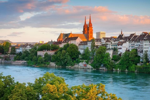 View of the Basel Cathedral in the middle of the old town of Basel with the turquoise Rhine River in the foreground