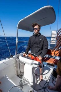 Man at the wheel in the cockpit on the deck of a sailing catamaran