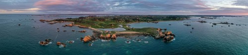 Panorama drone shot from the Atlantic Ocean onto the granite coast of Plougrescant with a view of the house between the rocks (Le gouffre de Plougrescant) at sunset