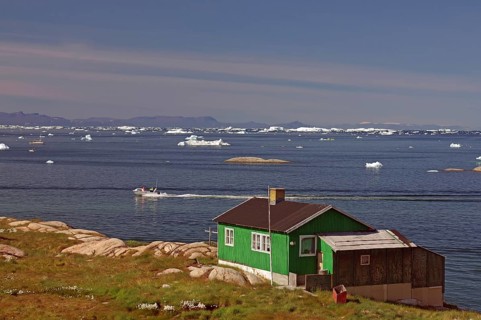 Simple dwelling house on the edge of an iceberg-covered bay
