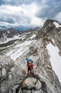 Hiker climbing metal ladder on rock