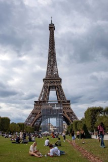 Locals and tourists sitting on a lawn in front of the Eiffel Tower