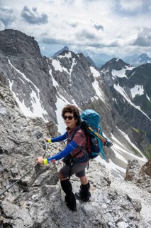 Mountaineer on a secured ridge trail with remnants of snow