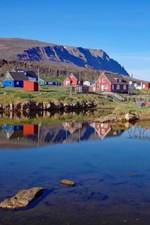 Wooden houses reflected in the water in front of mountains
