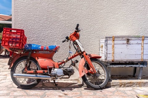 Old red scooter in front of a wall