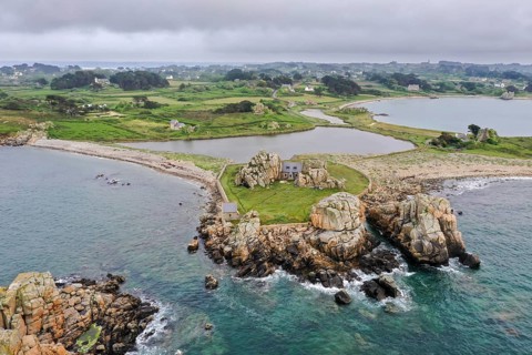Drone shot from the Atlantic Ocean onto the granite coast of Plougrescant with a view of the house between the rocks (Le gouffre de Plougrescant) in the morning