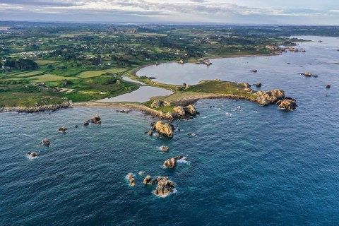 Wide angle drone shot from the Atlantic Ocean onto the granite coast of Plougrescant with a view of the house between the rocks (Le gouffre de Plougrescant)