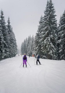 People skiing on the snowy slope of Bukovel ski resort in the Ukrainian Carpathian mountains. Snow falling scene