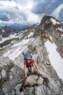 Hiker climbing metal ladder on rock