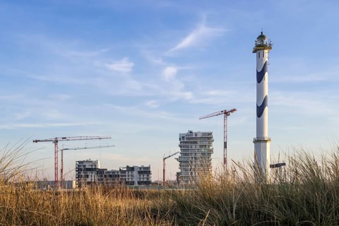 Lange Nelle lighthouse and new flats under construction for the Oosteroever real estate project in the port of Ostend on the Belgian North Sea coast