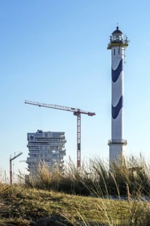 Lange Nelle lighthouse and new flats under construction for the Oosteroever real estate project in the port of Ostend on the Belgian North Sea coast