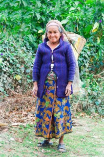 Old Nepalese woman carrying stones for road construction on her back