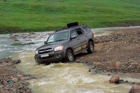 Off-road vehicle crossing a mountain river at Tosor Pass