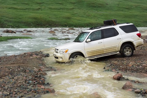 Off-road vehicle crossing a mountain river at Tosor Pass