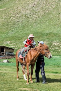 Kyrgyz man helping his girl on a horse