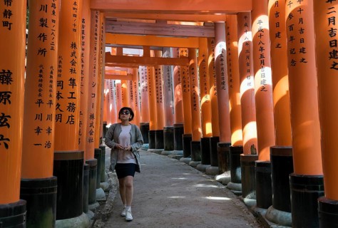 Young woman on a pathway lined with torii gates