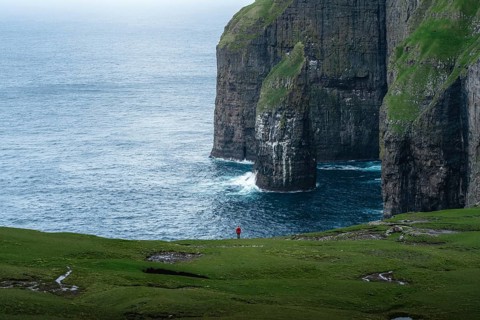 A person standing in the distance in front of Asmundarstakkur cliff