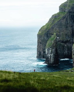 A person standing in the distance in front of Asmundarstakkur cliff