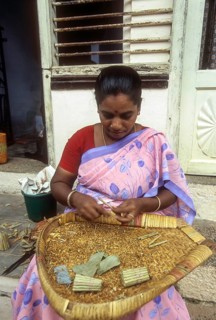 Woman rolling Beedis by sitting on the steps in front of her house