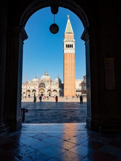 View through an archway onto St Mark's Square with the Campanile bell tower and the Basilica of St Mark