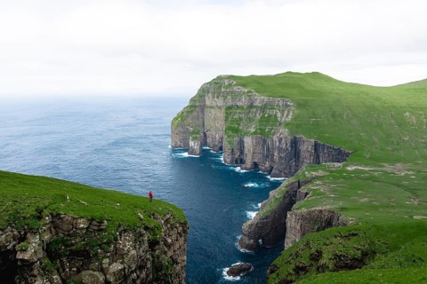 A person standing in the distance in front of Asmundarstakkur cliff