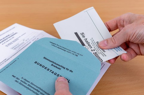 Man puts his folded ballot paper into the ballot paper envelope for the election of members of the German Bundestag on 26.09.2021
