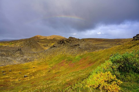 Rainbow over volcanic landscape and colourful autumn colours