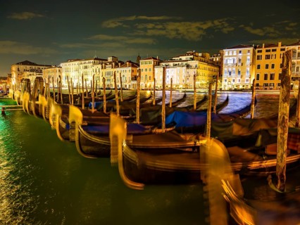 Gondolas in front of historic house facades in the Grand Canal at night