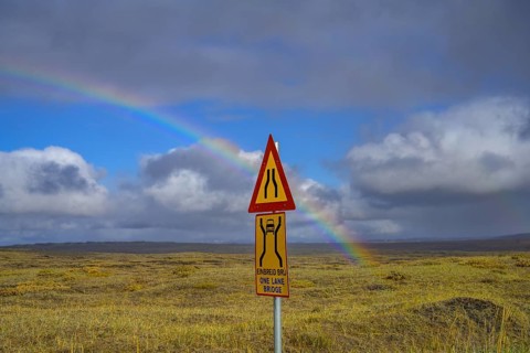Rainbow over the autumn coloured landscape and road sign one lane bridge