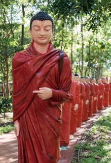 Statues of monks walking behind Buddha