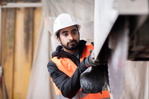 Technician with beard and helmet works in a workshop