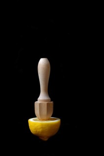 Lemon and lemon squeezer against a black background