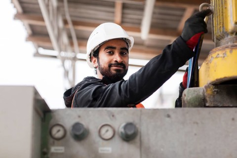 Technician with beard and helmet works in a workshop