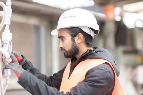 Technician with beard and helmet works in a workshop