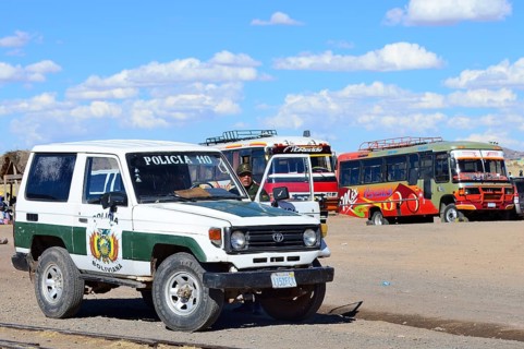 Policeman with police car in front of waiting public buses