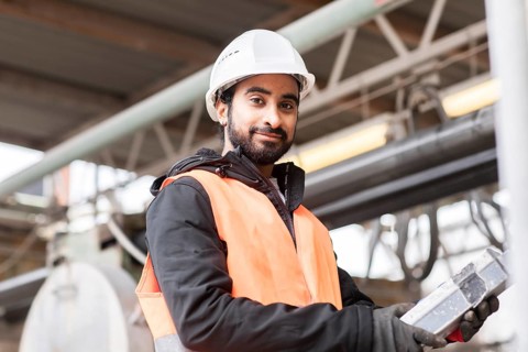 Technician with beard and helmet works in a workshop