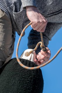 Young man tying a knot in a rope of a fender