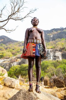 Traditional dressed young girls from the Laarim tribe standing on a rock