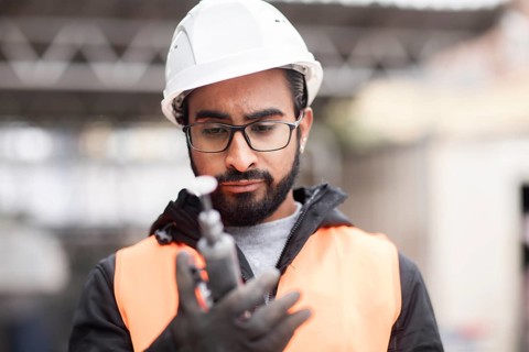 Technician with beard and helmet works in a workshop