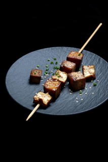 Fried tofu cubes with wooden skewer on plate